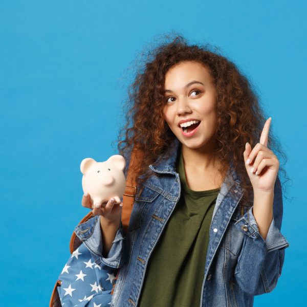 Young african american girl teen student in denim clothes, backpack hold pig isolated on blue wall background studio portrait. Education in high school university college concept. Mock up copy space